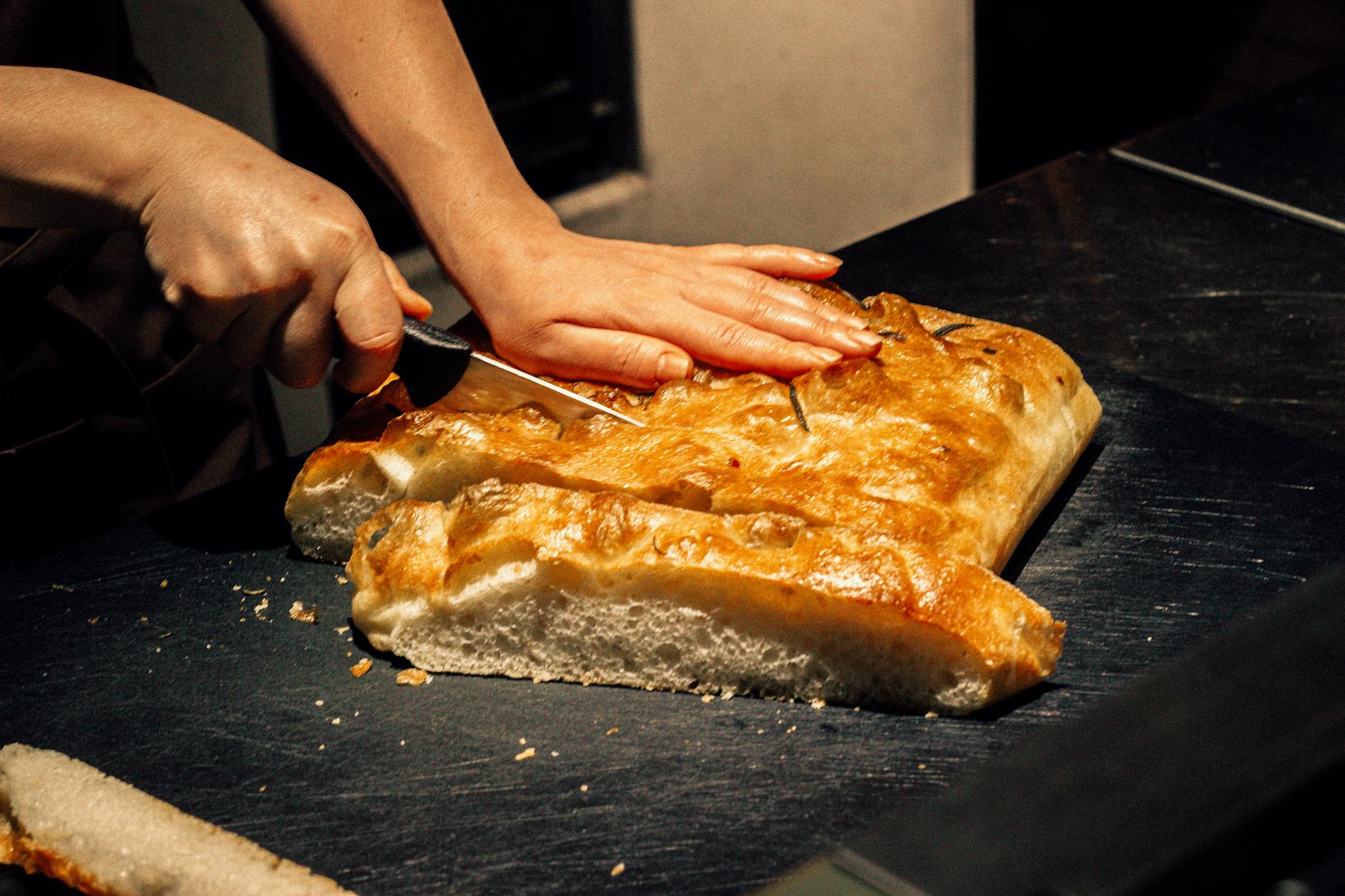 Krojona prostokątna focaccia na ciemnym blacie