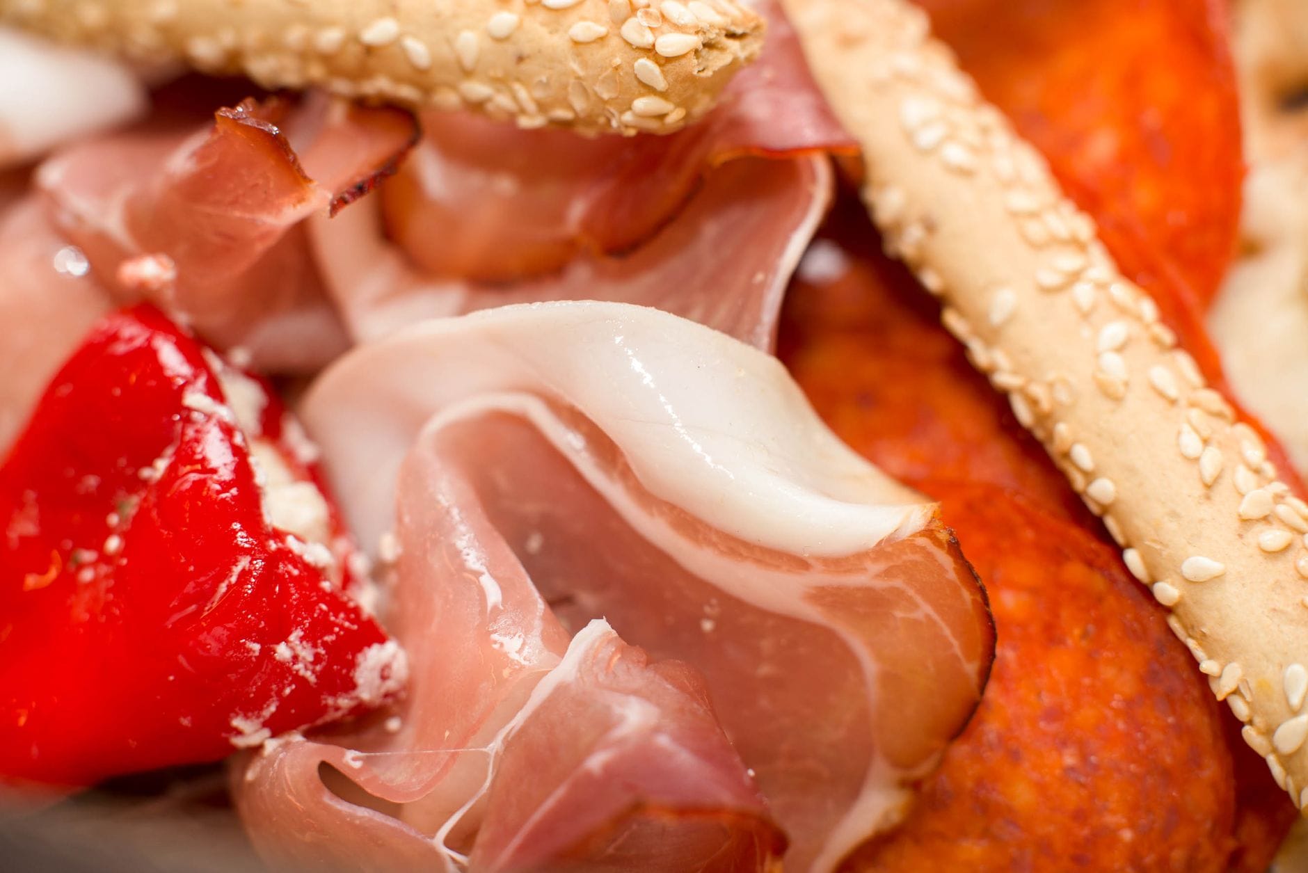 Deska włoskich przystawek z prosciutto, pieczoną papryką i paluszkami sezamowymi