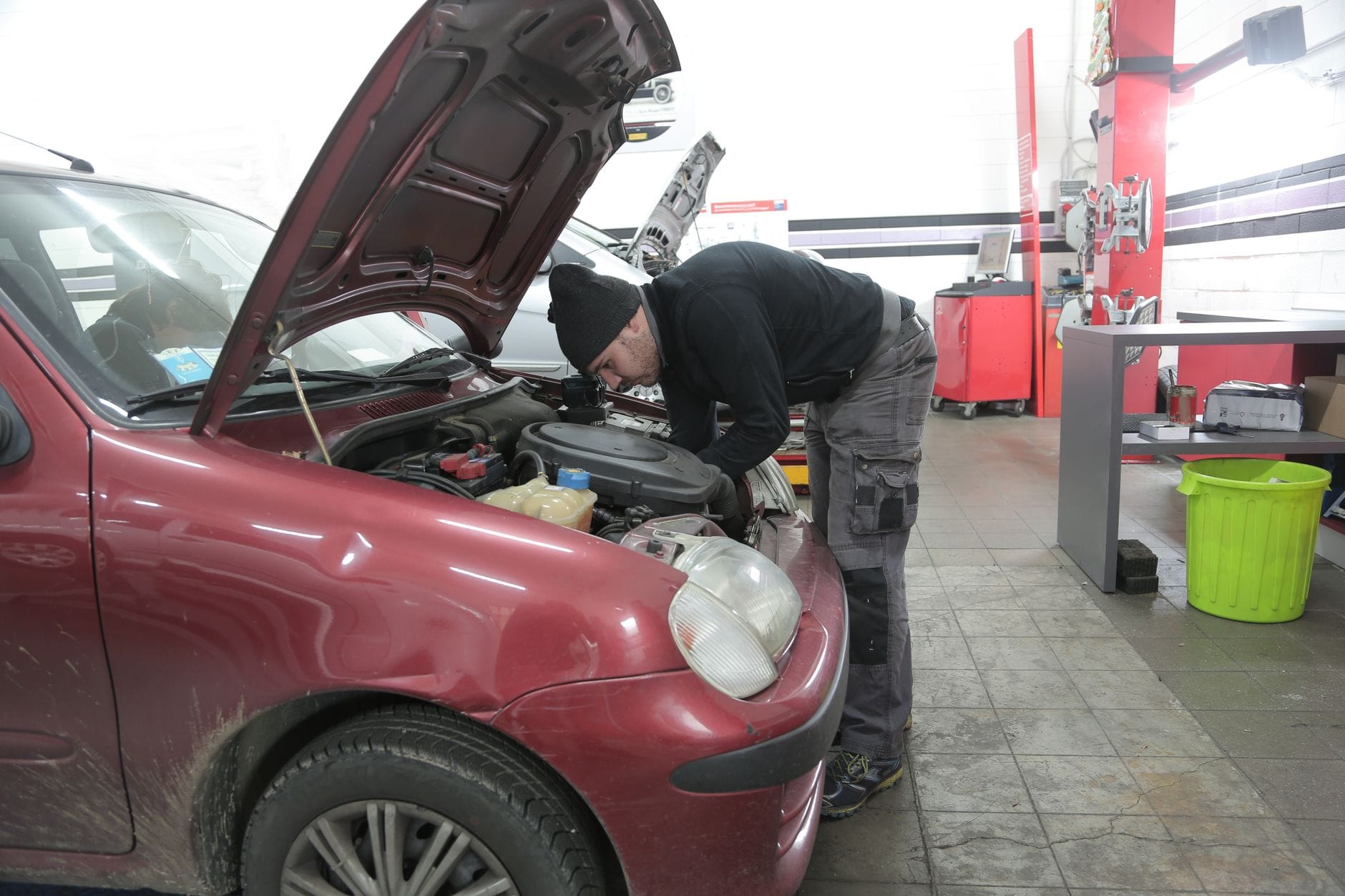 Mechanik sprawdza silnik czerwonego Opla w warsztacie