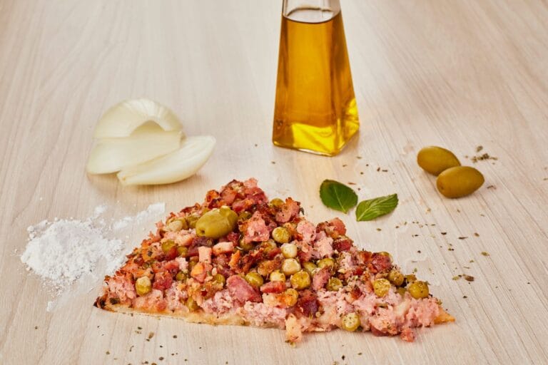 Kawałek włoskiej pizzy z oliwkami, cebulą i oliwą na drewnianym blacie